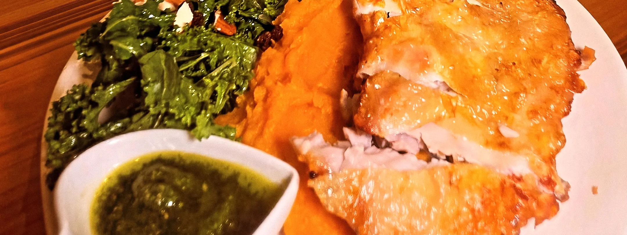 The Golden Chicken en la mesa de madera, con su salsa en un cuenco con forma de corazón y el local al fondo